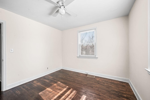 empty room with a ceiling fan, dark wood-style flooring, visible vents, and baseboards