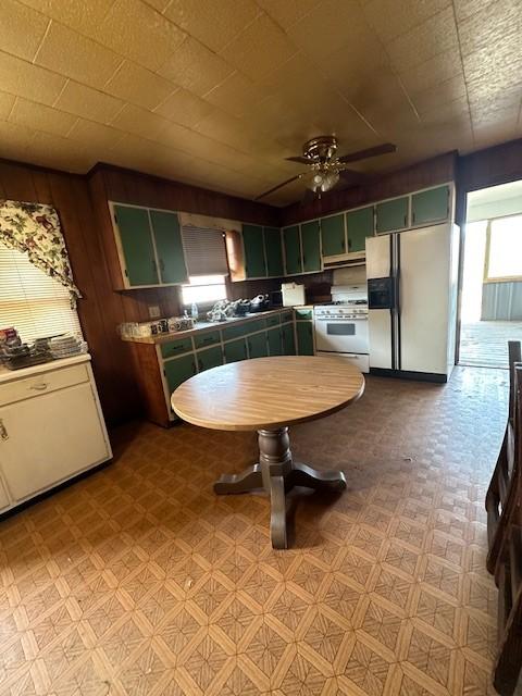 kitchen with green cabinetry, white range with gas cooktop, refrigerator with ice dispenser, and light floors