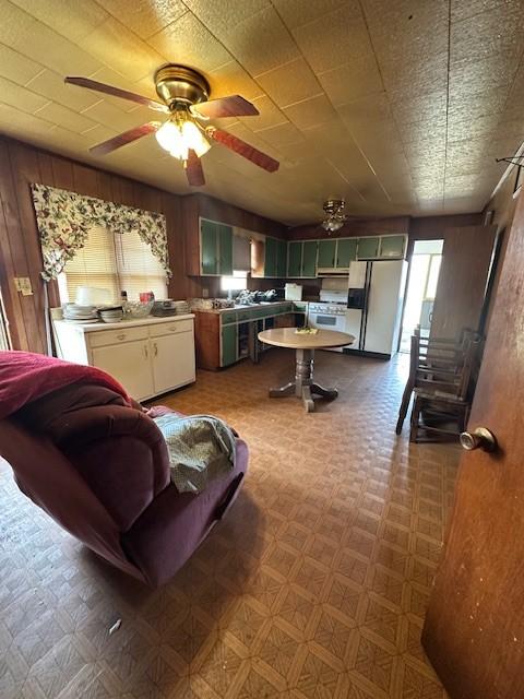 kitchen with white appliances, light countertops, wooden walls, and tile patterned floors