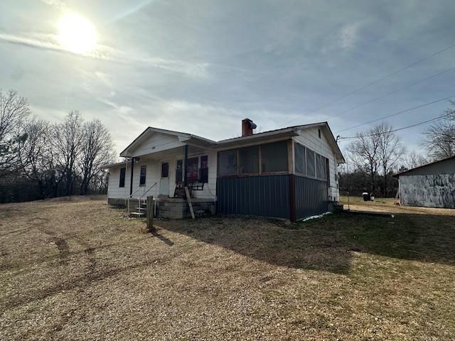 view of front of house featuring a front lawn, a chimney, and a sunroom