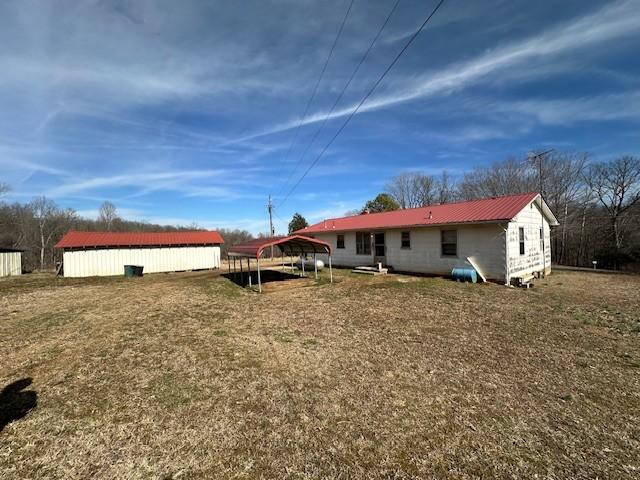 back of property featuring metal roof and a yard