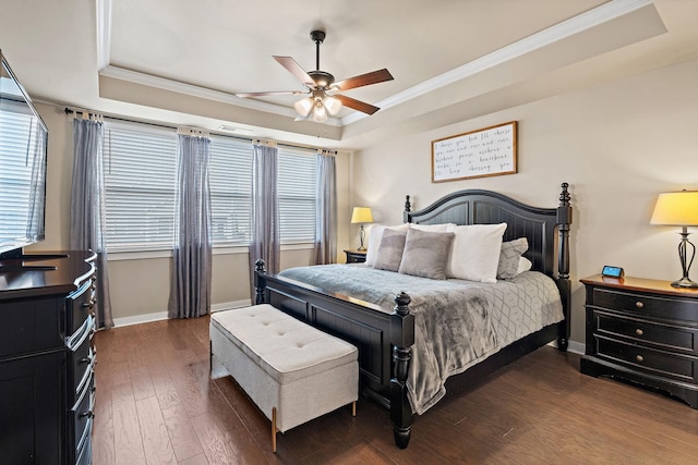 bedroom with dark wood-style floors, a raised ceiling, ornamental molding, and baseboards