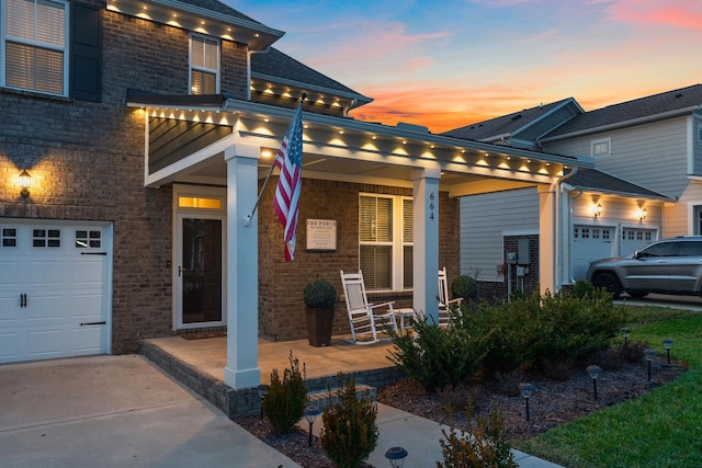 view of front of property with a garage, covered porch, and brick siding