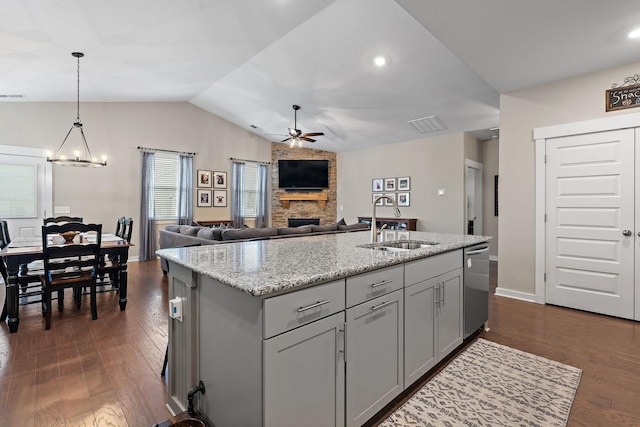 kitchen with dishwasher, an island with sink, open floor plan, hanging light fixtures, and a sink