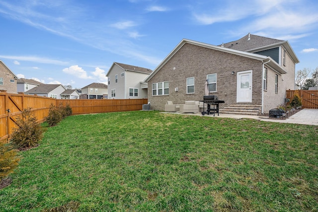 rear view of house featuring a patio, brick siding, a lawn, and a fenced backyard