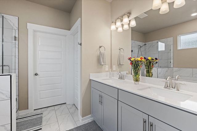 full bath with marble finish floor, double vanity, a stall shower, and a sink