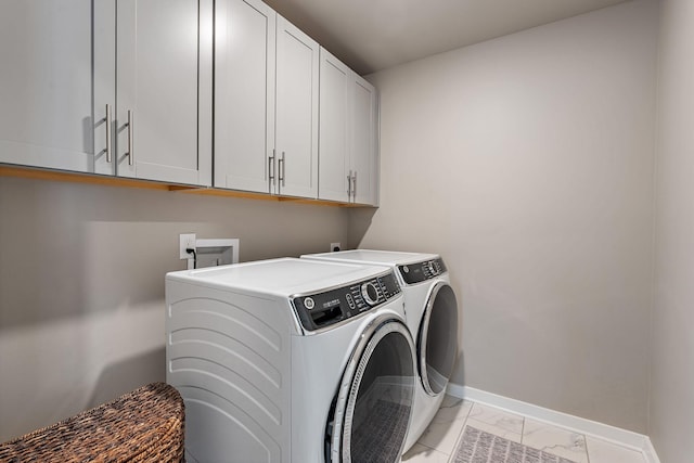 washroom with cabinet space, baseboards, marble finish floor, and independent washer and dryer