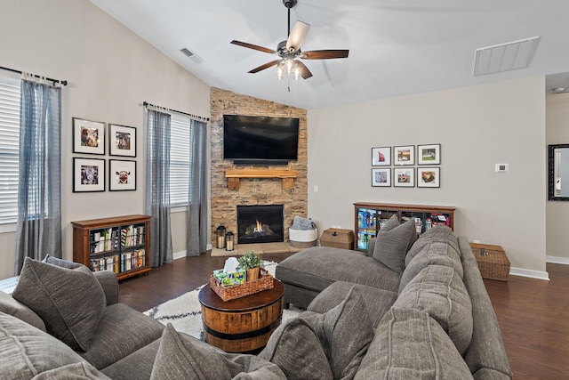 living area with dark wood-type flooring, lofted ceiling, visible vents, and a stone fireplace