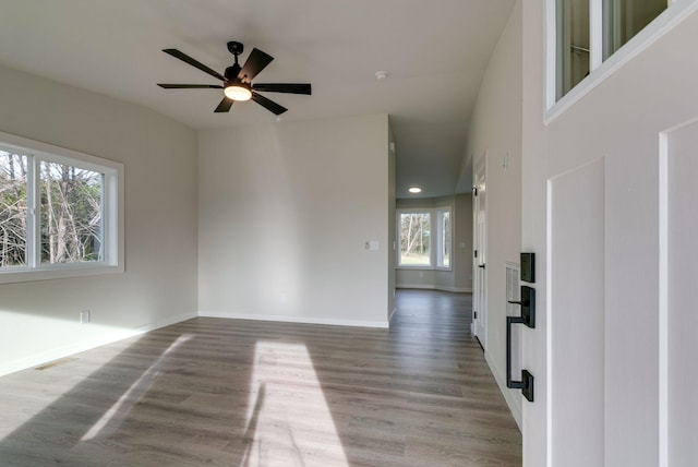 spare room featuring visible vents, ceiling fan, baseboards, and wood finished floors