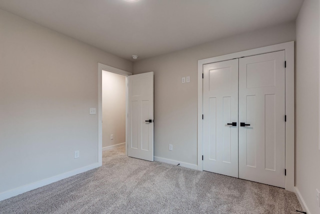 unfurnished bedroom featuring baseboards, a closet, and light colored carpet