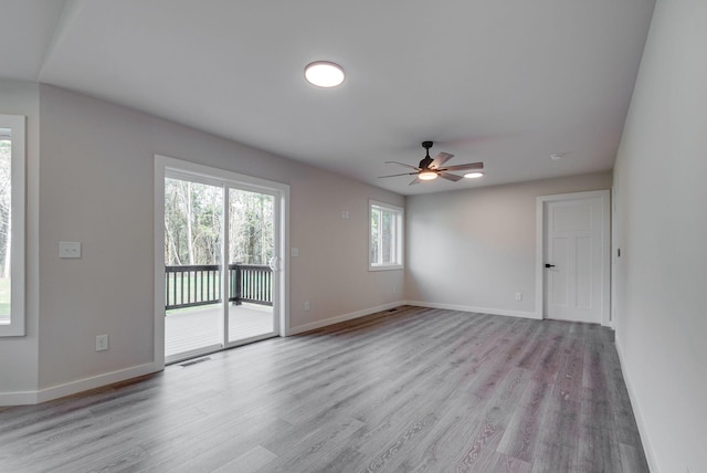 spare room with visible vents, ceiling fan, light wood-style flooring, and baseboards