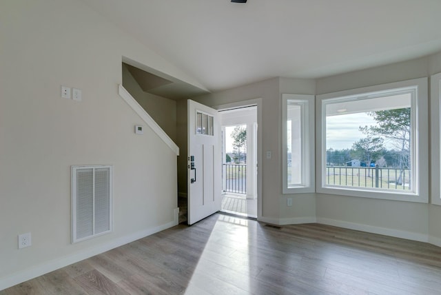 entryway with light wood-type flooring, visible vents, lofted ceiling, and baseboards