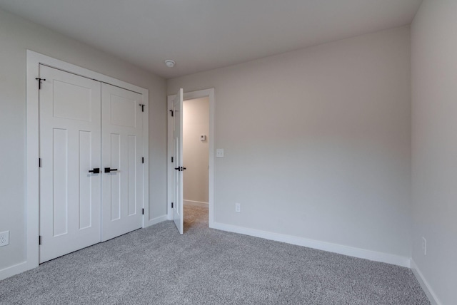 unfurnished bedroom with carpet floors, baseboards, and a closet