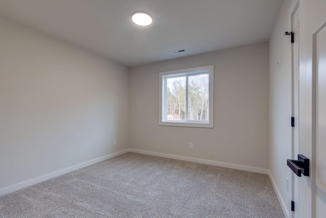 empty room with carpet flooring, visible vents, and baseboards