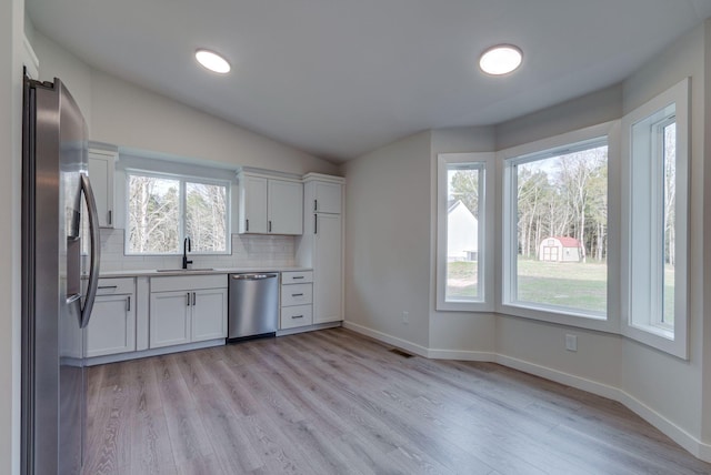 kitchen with a sink, appliances with stainless steel finishes, white cabinets, and light countertops