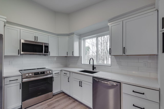 kitchen with white cabinets, tasteful backsplash, stainless steel appliances, and a sink