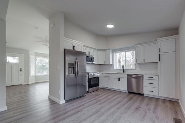 kitchen featuring visible vents, white cabinets, light countertops, appliances with stainless steel finishes, and decorative backsplash