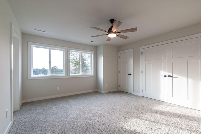 unfurnished bedroom featuring baseboards, ceiling fan, visible vents, and light colored carpet