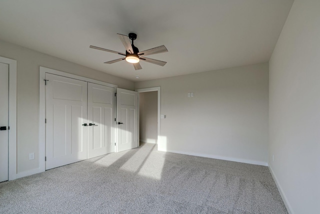 unfurnished bedroom with carpet floors, a closet, baseboards, and a ceiling fan