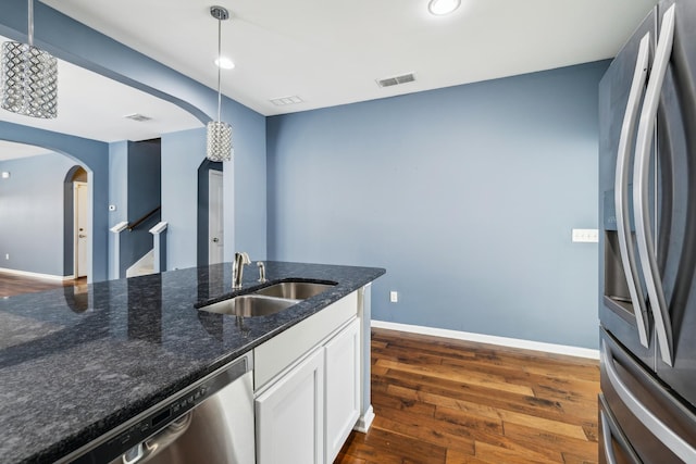 kitchen featuring visible vents, white cabinets, appliances with stainless steel finishes, decorative light fixtures, and a sink