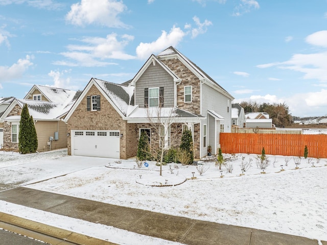 view of front of home featuring a garage, brick siding, fence, stone siding, and driveway