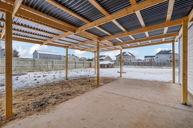 snow covered patio featuring a fenced backyard and a residential view