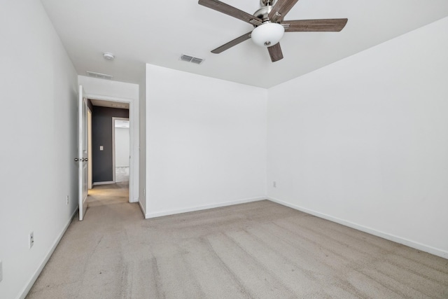 empty room featuring light carpet, ceiling fan, visible vents, and baseboards