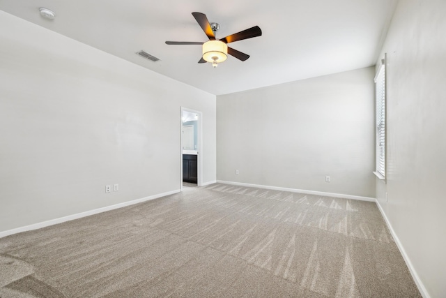 unfurnished room with ceiling fan, light colored carpet, visible vents, and baseboards