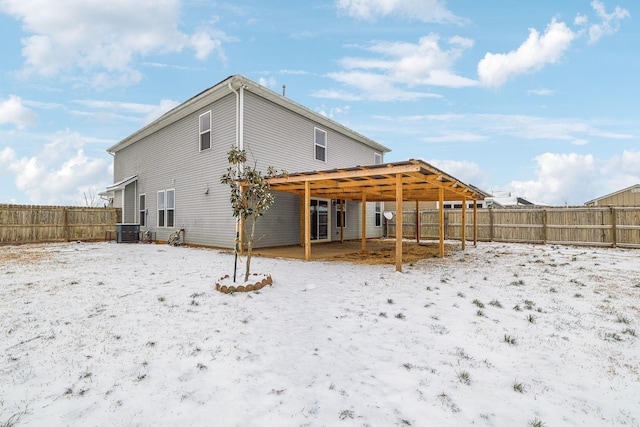 snow covered rear of property featuring a fenced backyard and central AC unit