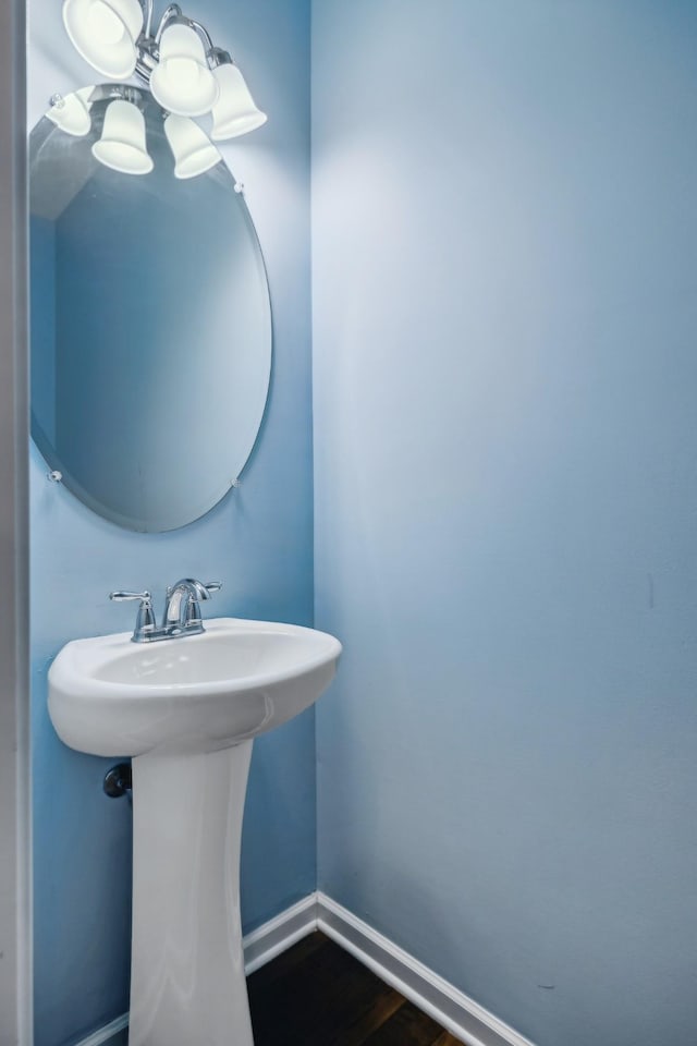 bathroom with baseboards, a chandelier, a sink, and wood finished floors