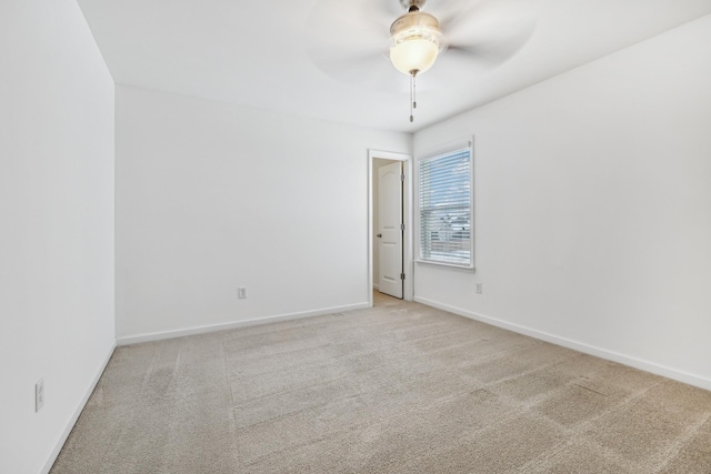 empty room with baseboards, a ceiling fan, and light colored carpet