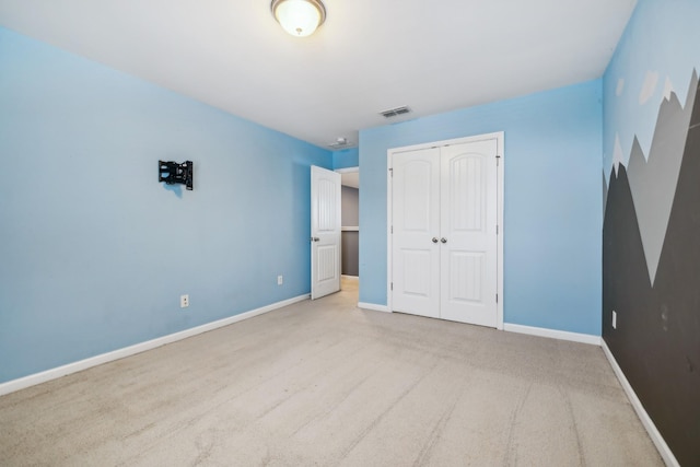 unfurnished bedroom featuring a closet, light colored carpet, visible vents, and baseboards