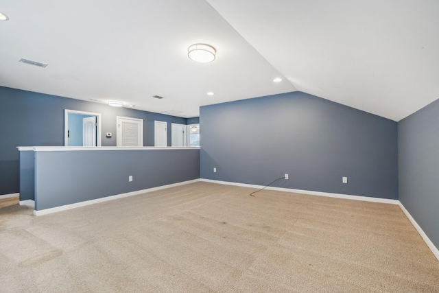 spare room with lofted ceiling, visible vents, light carpet, and baseboards