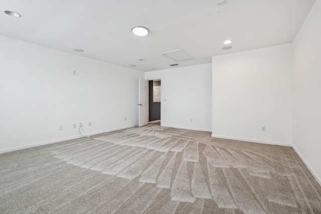 empty room with attic access, recessed lighting, light colored carpet, and baseboards