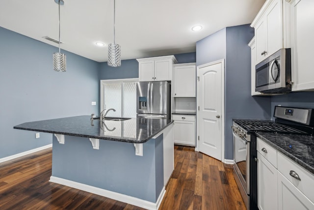 kitchen featuring white cabinets, stainless steel appliances, a sink, and decorative light fixtures