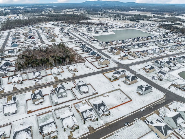 snowy aerial view with a residential view and a water and mountain view