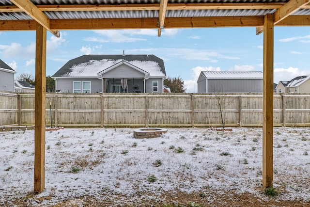 snowy yard featuring an outdoor fire pit and a fenced backyard