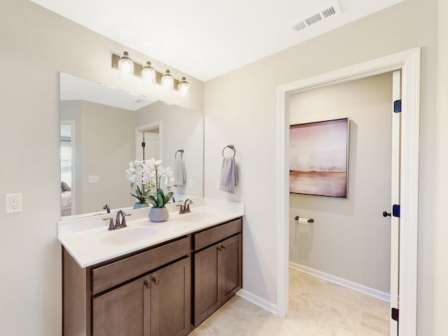 bathroom featuring double vanity, a sink, visible vents, and baseboards