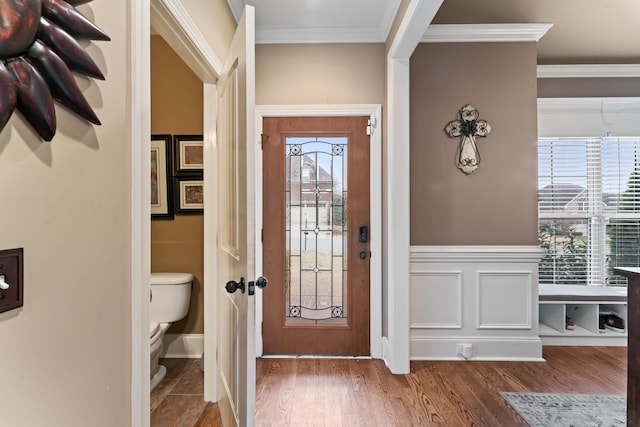 entryway featuring ornamental molding, a wainscoted wall, and dark wood finished floors