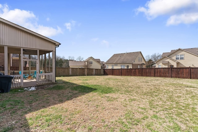 view of yard with a residential view, a sunroom, and a fenced backyard