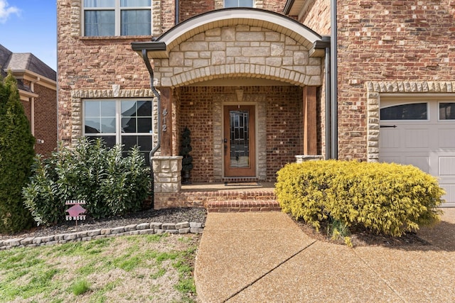 view of exterior entry featuring stone siding, brick siding, and an attached garage