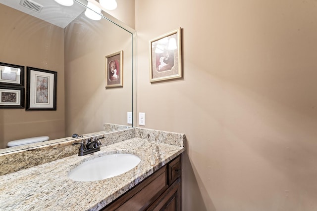 half bath featuring toilet, vanity, and visible vents