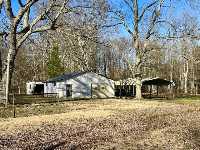 view of home's exterior featuring a detached carport, dirt driveway, a pole building, and an outbuilding