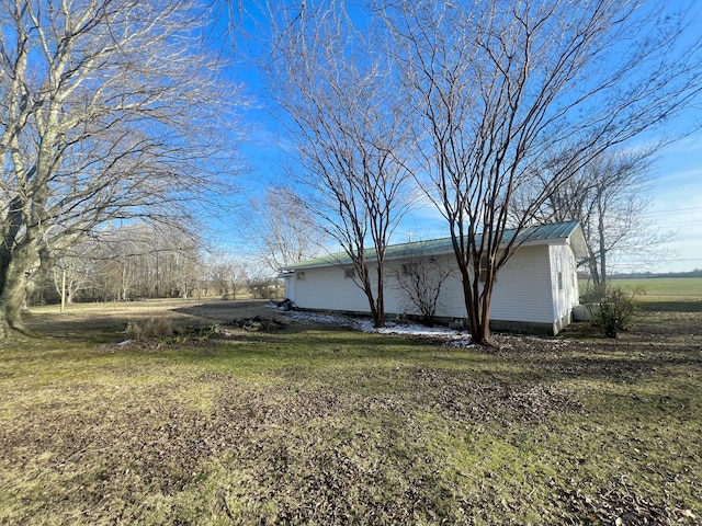 view of home's exterior with metal roof and a lawn