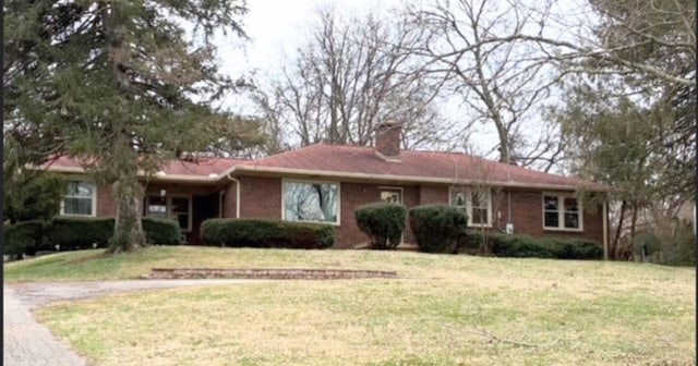 ranch-style home with a front lawn, a chimney, and brick siding