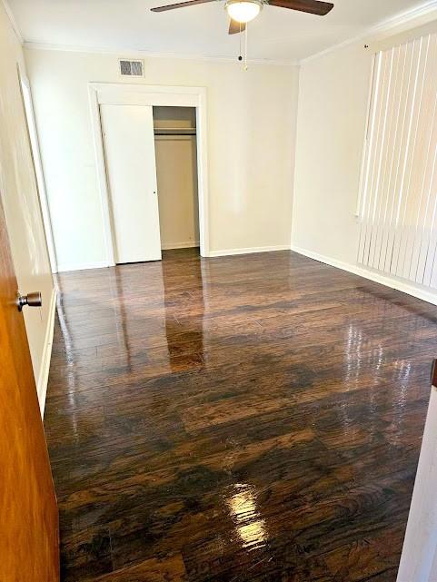 unfurnished bedroom with ornamental molding, dark wood-style flooring, visible vents, and baseboards