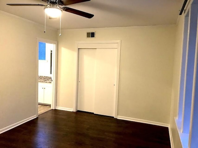 unfurnished bedroom featuring baseboards, visible vents, ornamental molding, dark wood-style flooring, and a closet