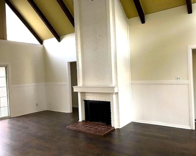 unfurnished living room featuring a wainscoted wall, high vaulted ceiling, a brick fireplace, and beam ceiling