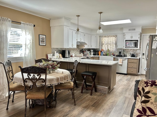 kitchen featuring a sink, stainless steel appliances, a peninsula, and crown molding