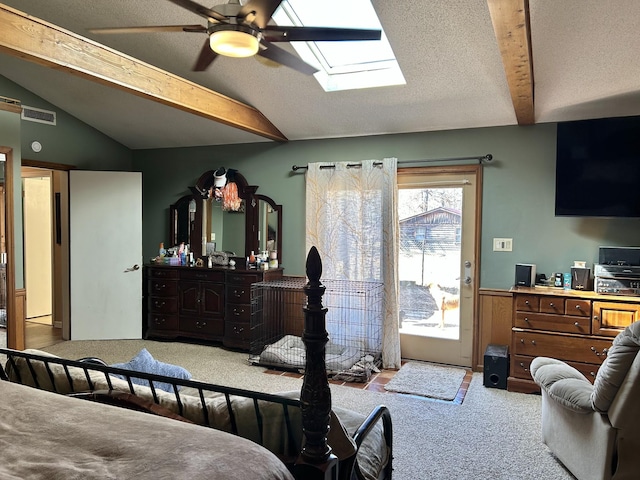 carpeted bedroom with a wainscoted wall, lofted ceiling with skylight, visible vents, a textured ceiling, and access to exterior